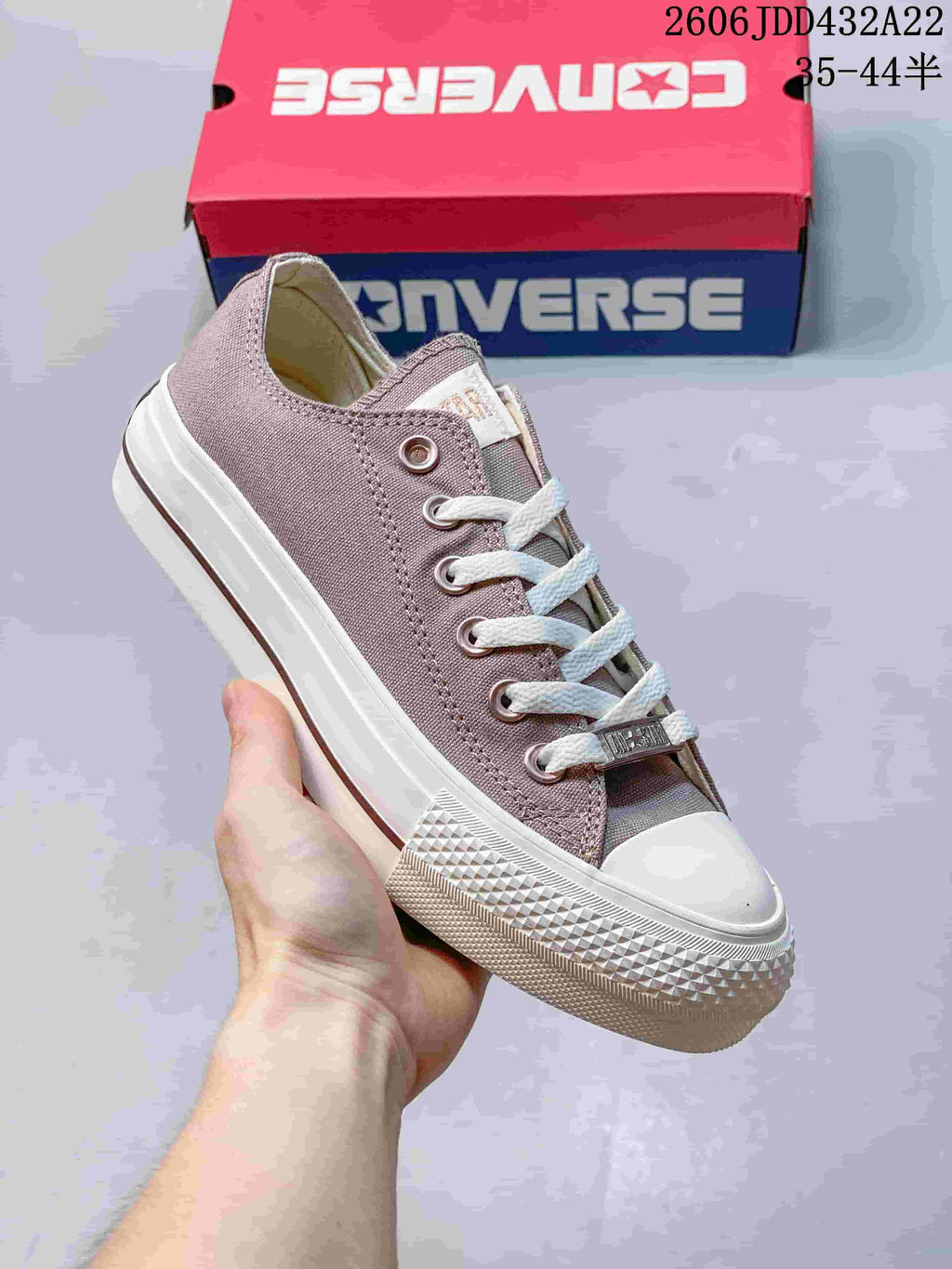 Close view of a mauve low-top sneaker with metal eyelets, white laces, and a white rubber sole