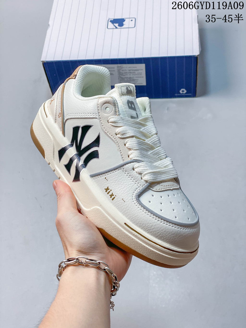 Angled view of a white MLB sneaker with a dark graphic on the side