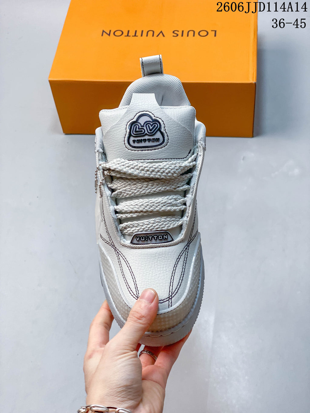 Front view highlighting the tongue emblem, thick laces, and contrast stitching of a white Trainer sneaker.