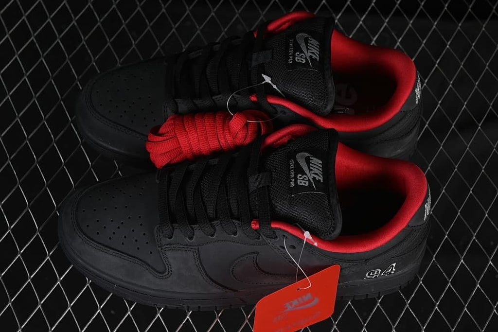 Pair of black low-top sneakers with red lining and an additional red lace set