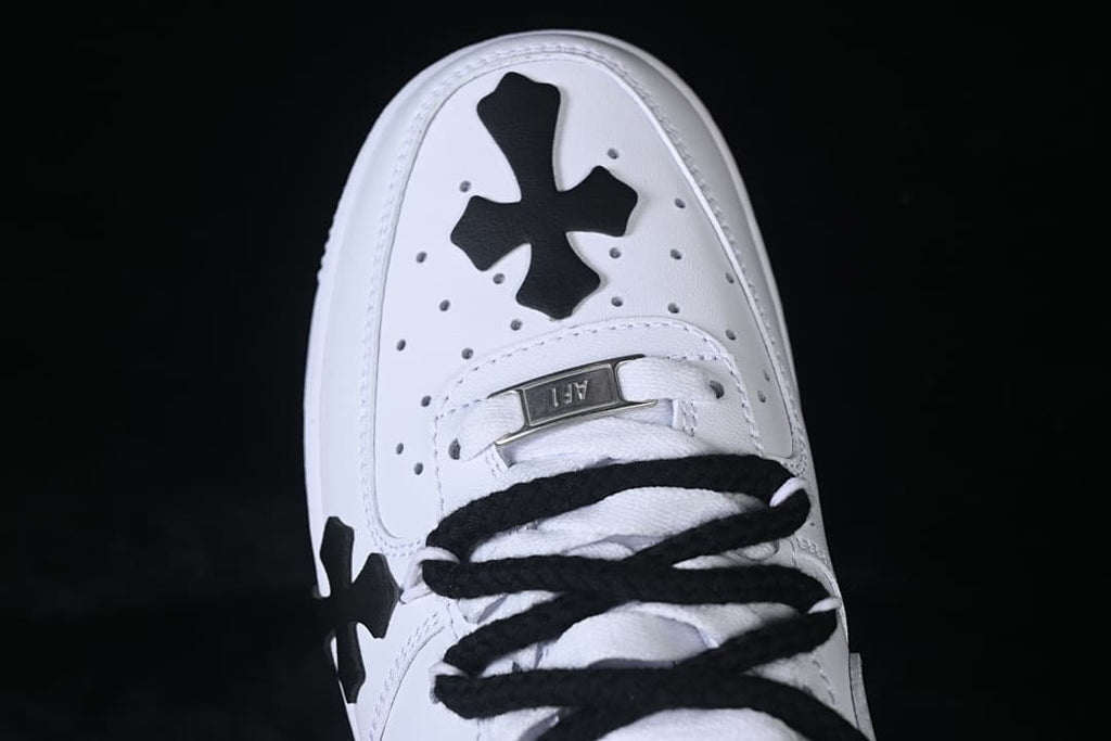 Top view of the toe, showing a black cross detail, perforations, and black laces.