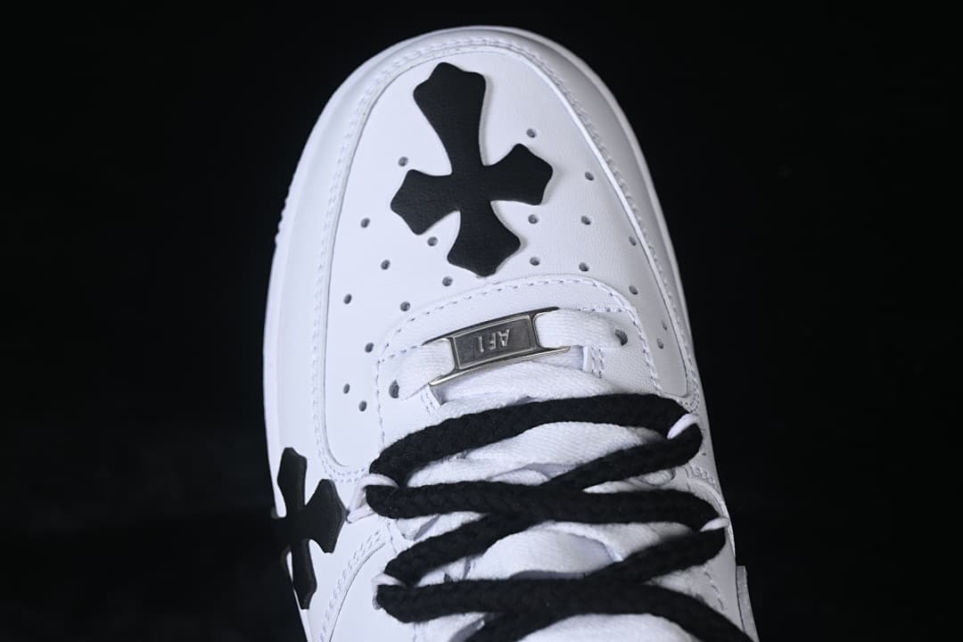 Top view of the toe, showing a black cross detail, perforations, and black laces.