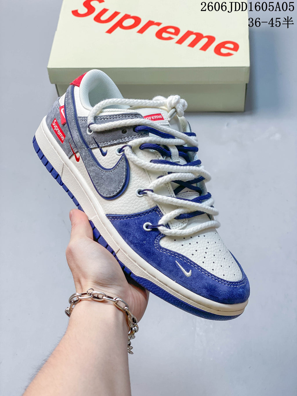 Angled side view of a white, blue, and gray low-top sneaker with layered accents