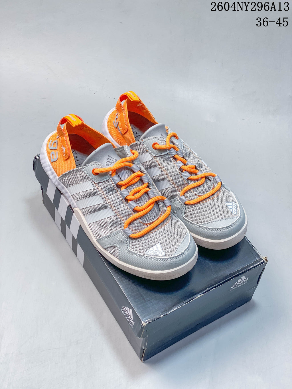 Pair of light gray adidas TERREX shoes with orange laces and orange heel accents.