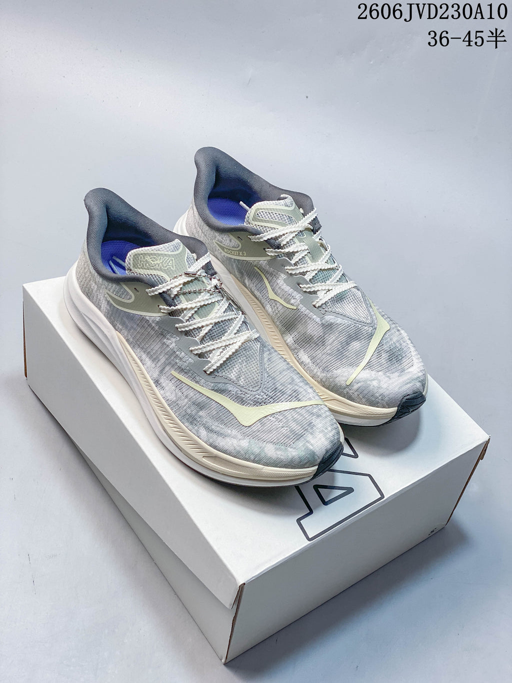 Pair of grey HOKA Rocket X 3 shoes with pale accents displayed on a box.