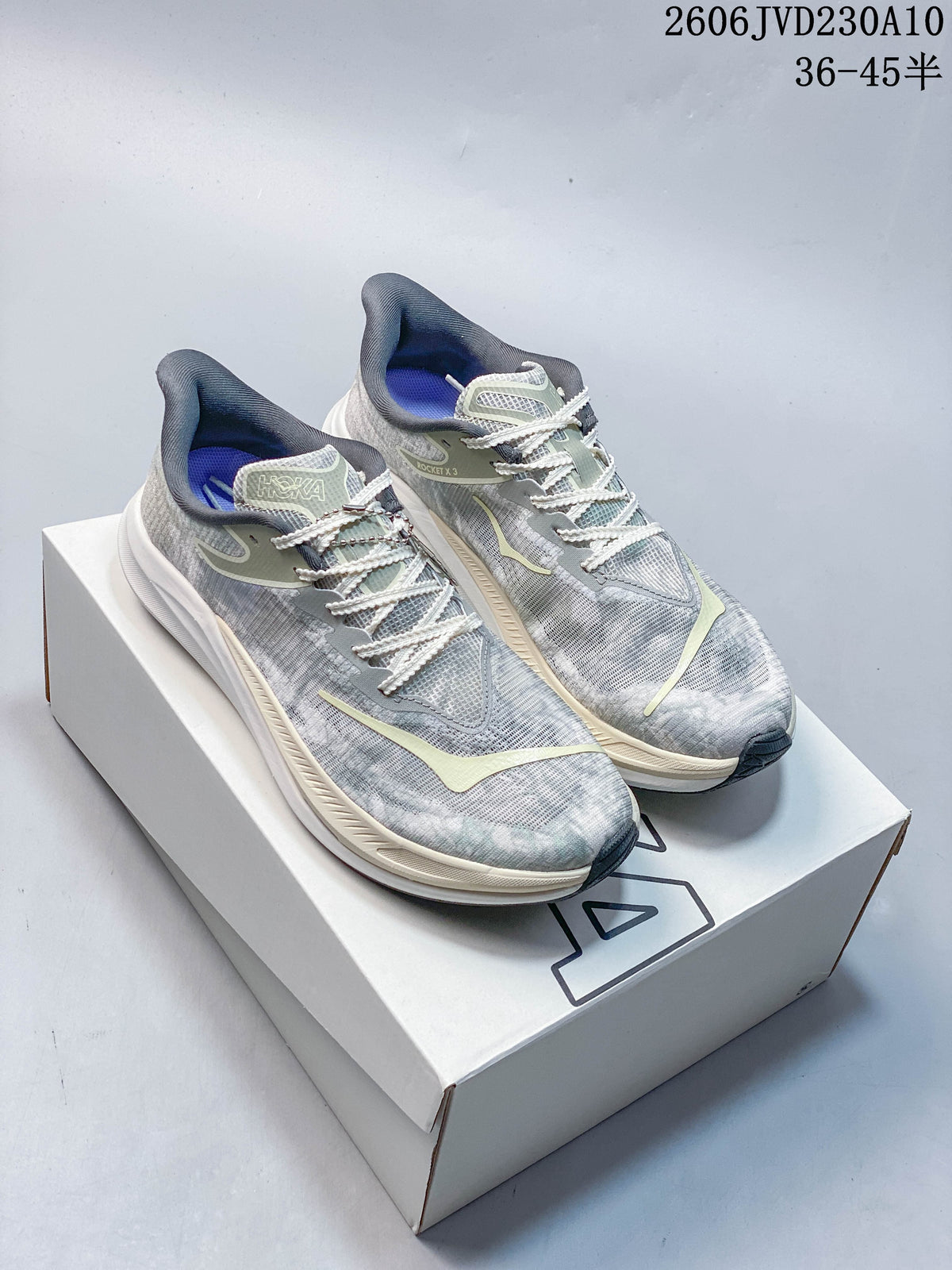 Pair of grey HOKA Rocket X 3 shoes with pale accents displayed on a box.