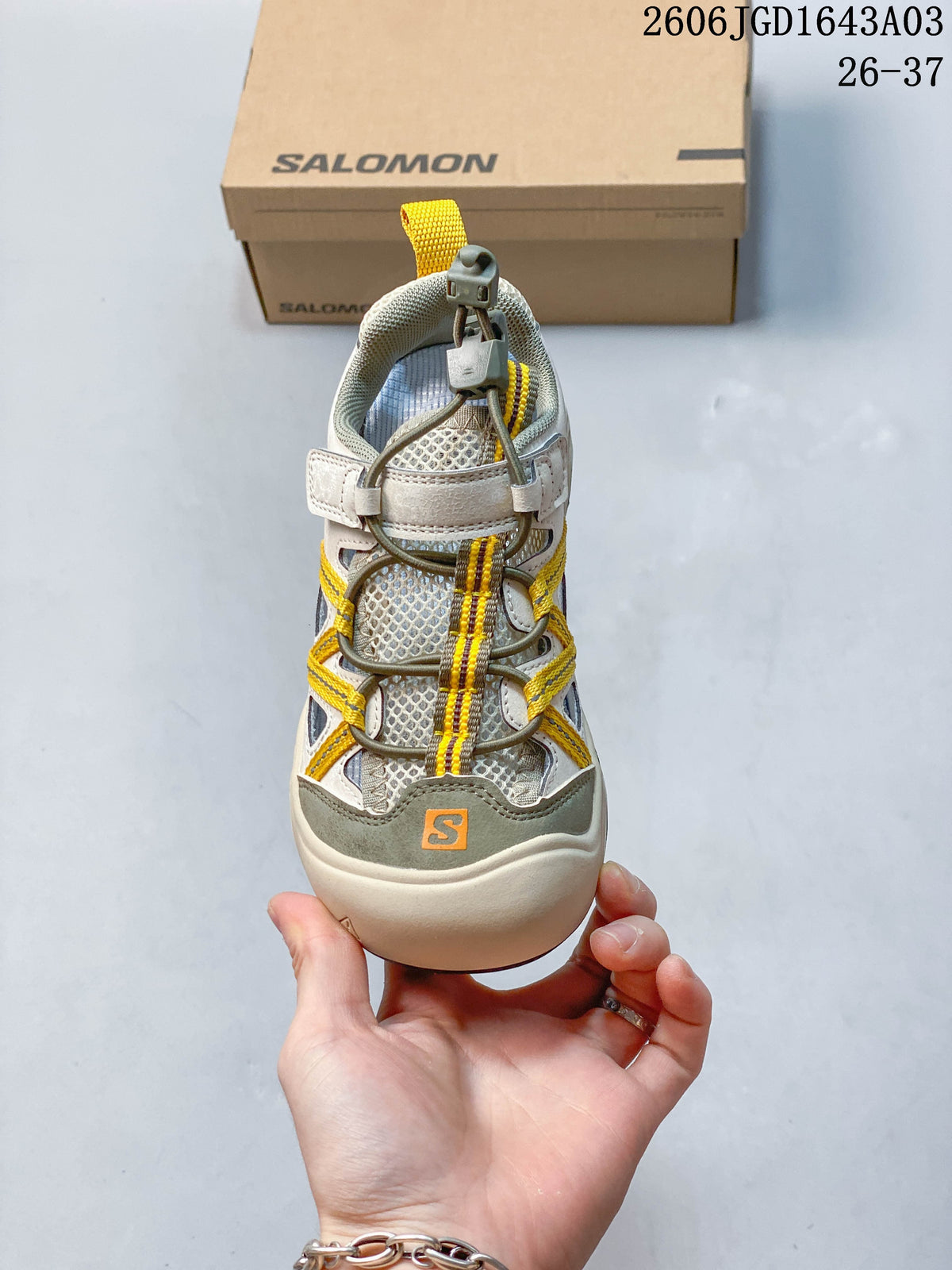 Front view of a beige and gray Salomon kids sneaker with toggle-style laces