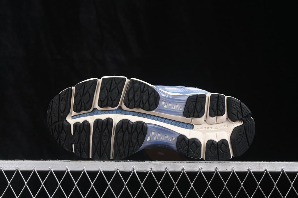 Underside view showing the segmented black rubber outsole, cream sole sections, and central blue channel.