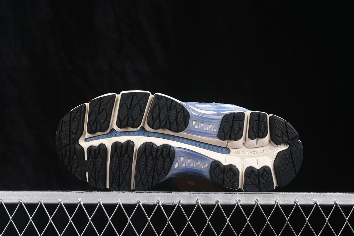 Underside view showing the segmented black rubber outsole, cream sole sections, and central blue channel.