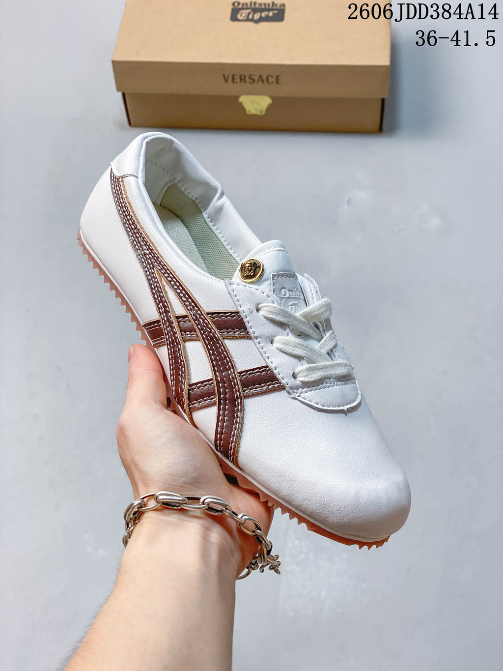 Angled view of the white sneaker with brown stripes and gum-colored outsole