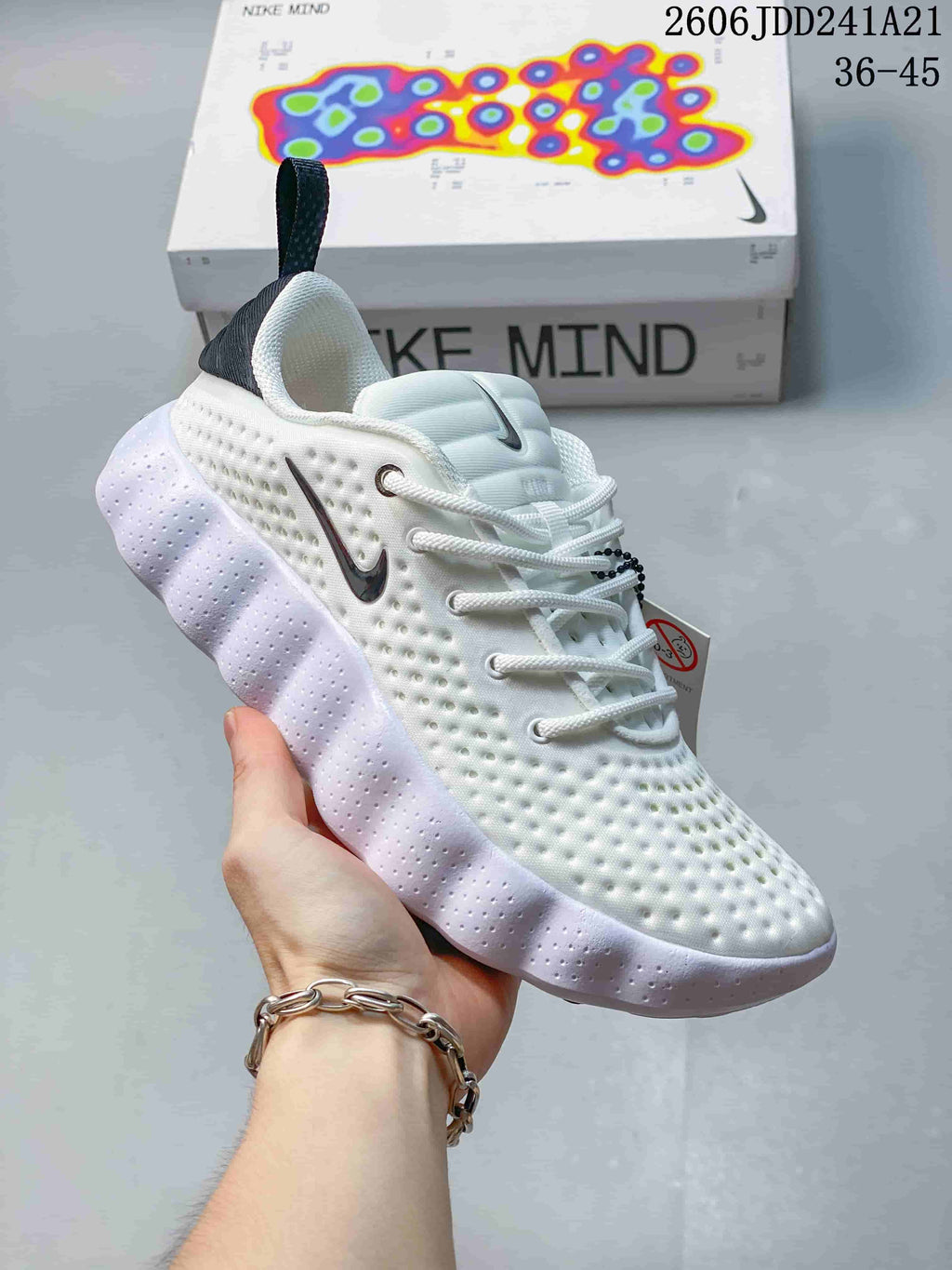 White Nike Mind 002 SP FK shoe with a thick pale outsole, shown beside its box.