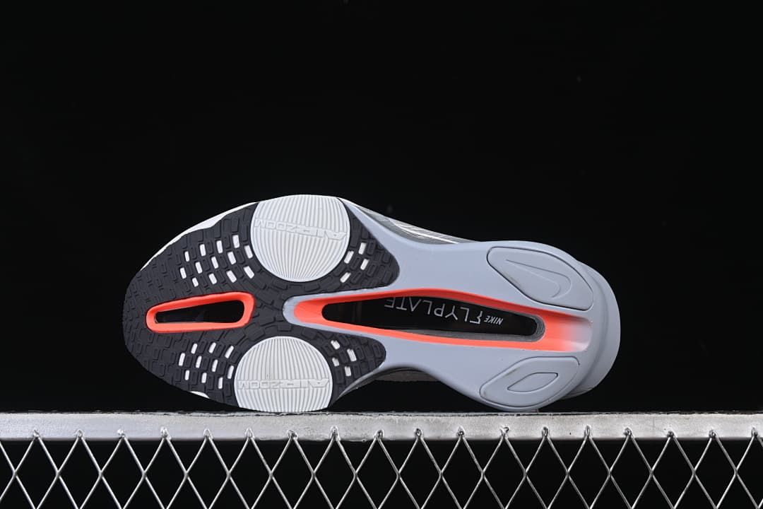 Underside view showing the outsole pattern and contrasting orange-red accents