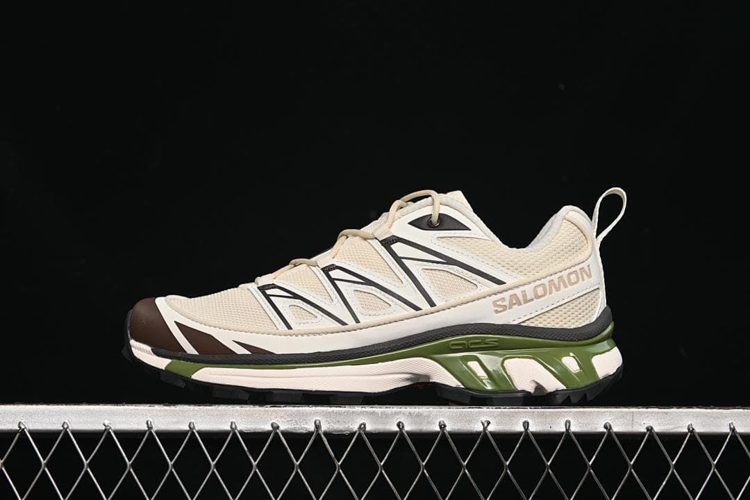 Side view of one cream sneaker with contrasting overlays and a green midsole section.