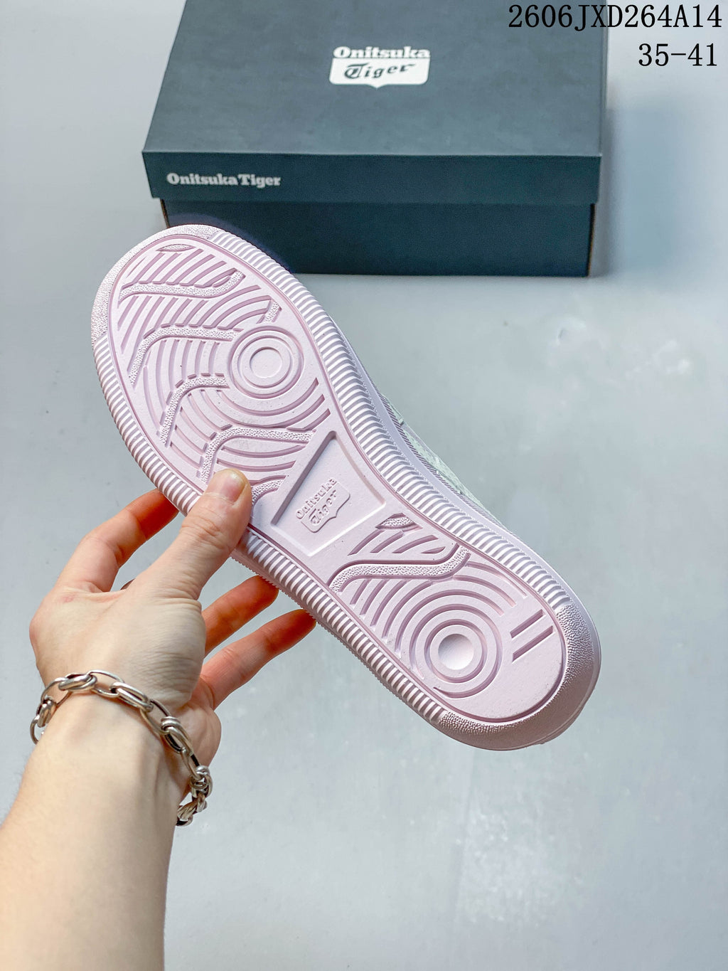 Underside of the pale pink sneaker showing a patterned sole and tread