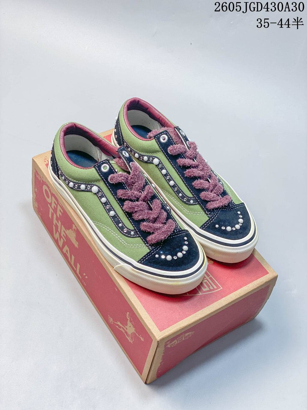 Pair of green and navy Vans LX Old Skool sneakers with pearl-like accents and plush mauve laces, displayed on a shoebox.