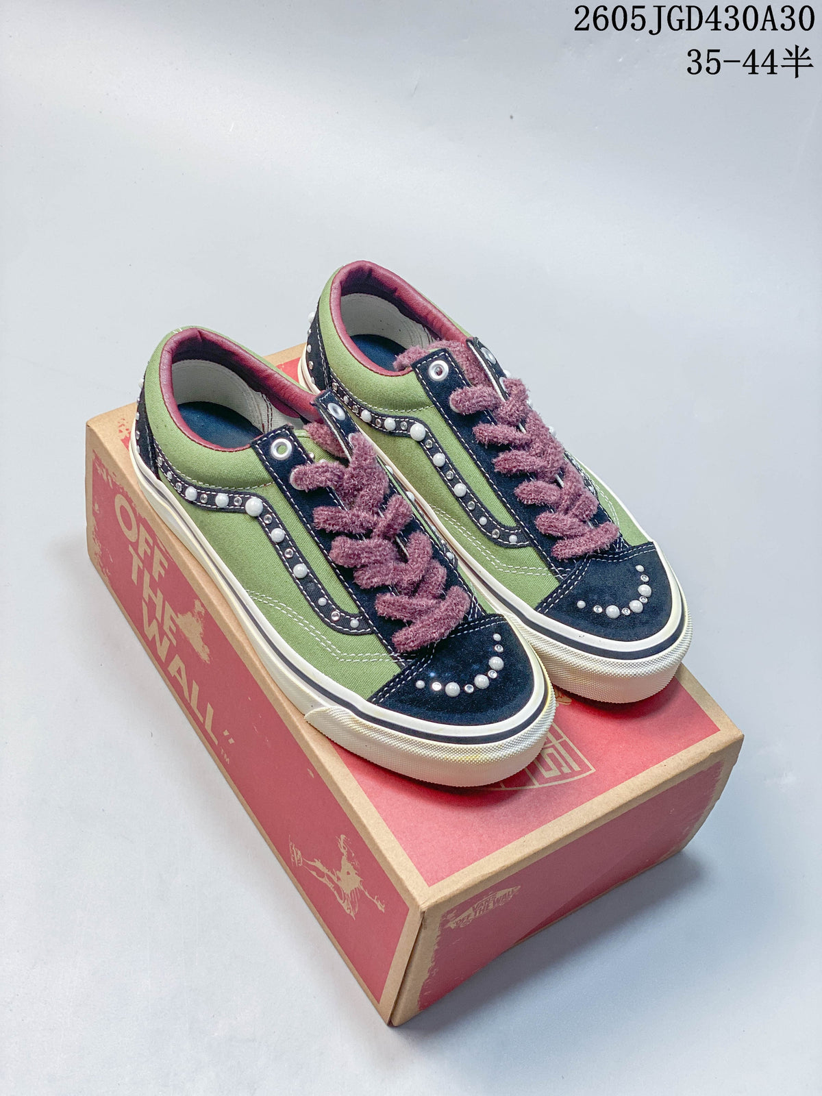Pair of green and navy Vans LX Old Skool sneakers with pearl-like accents and plush mauve laces, displayed on a shoebox.