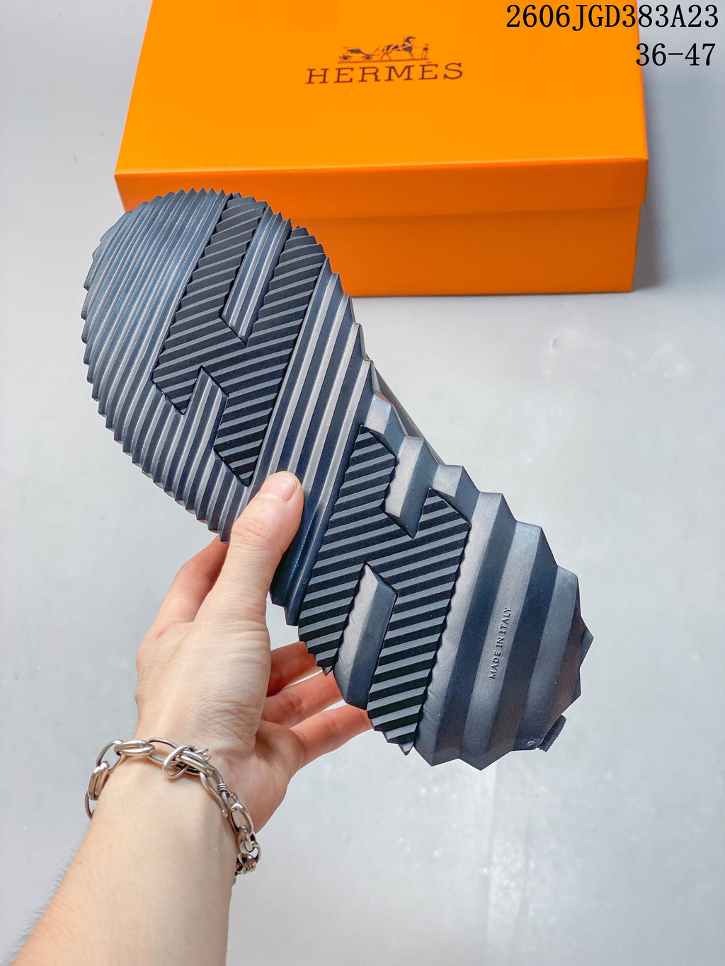 Close-up of the sneaker's sculpted ridged outsole, with an orange box in the background.