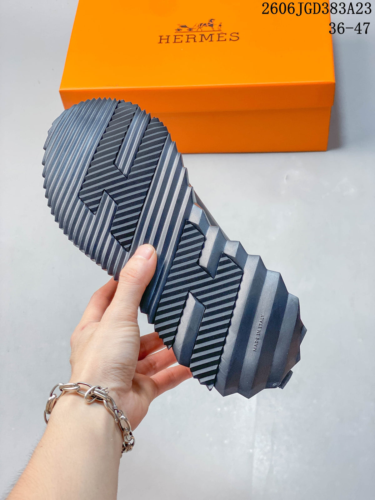 Close-up of the sneaker's sculpted ridged outsole, with an orange box in the background.