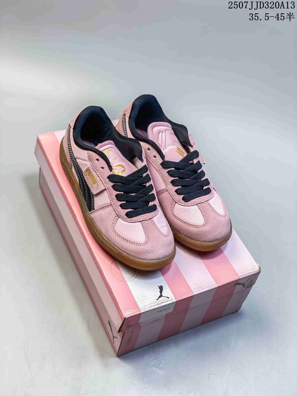 Pair of pink Puma Palermo sneakers with black laces and gum-colored soles on a striped box