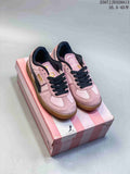 Pair of pink Puma Palermo sneakers with black laces and gum-colored soles on a striped box