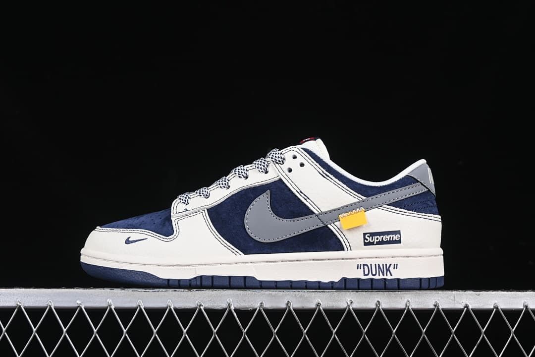 Side view of navy, off-white, and gray Nike SB Dunk Low sneakers with patterned laces and visible Supreme branding details.