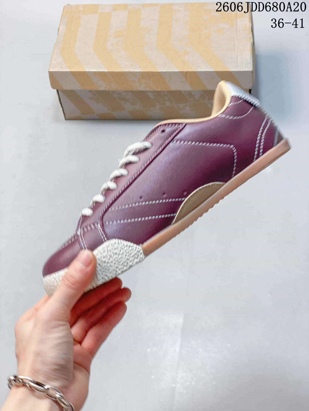 Side profile of a burgundy low-top sneaker with contrast stitching and a textured toe bumper