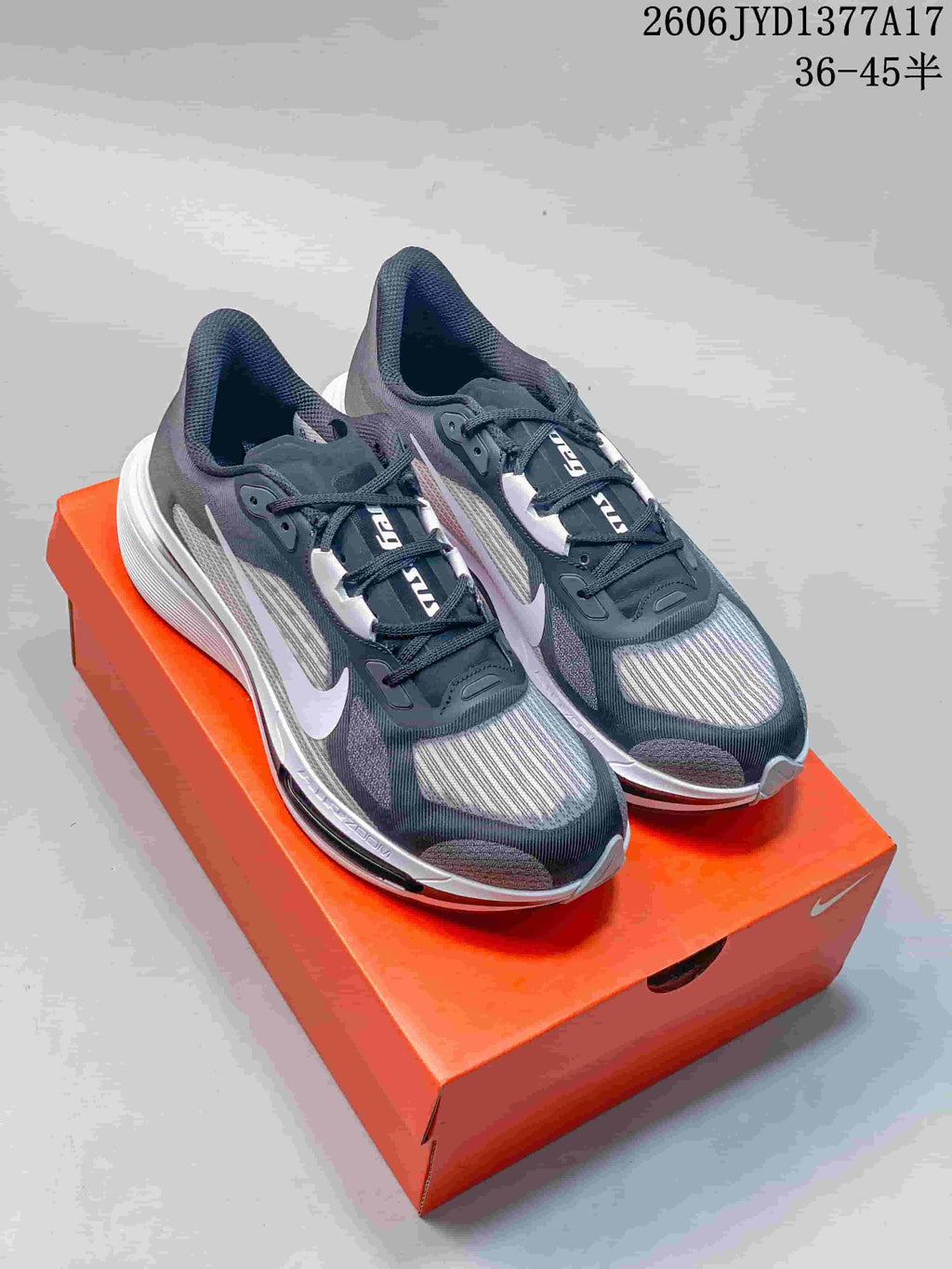 Pair of charcoal and gray Nike Zoom Plus sneakers with white accents on an orange shoe box