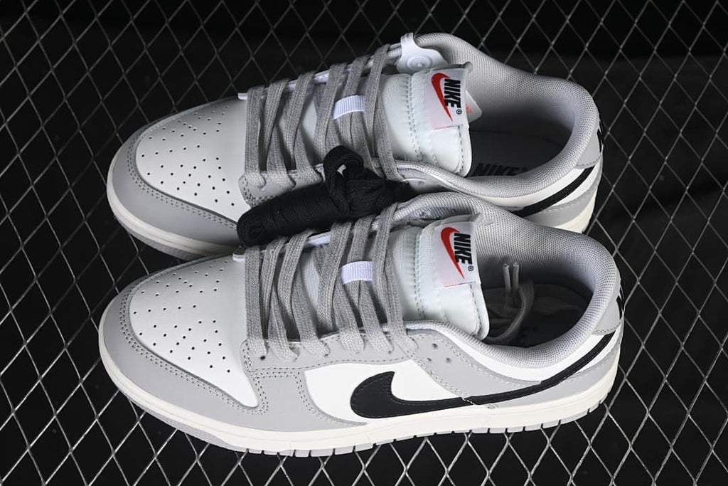 Pair of white, grey, and black low-top sneakers with alternate black laces