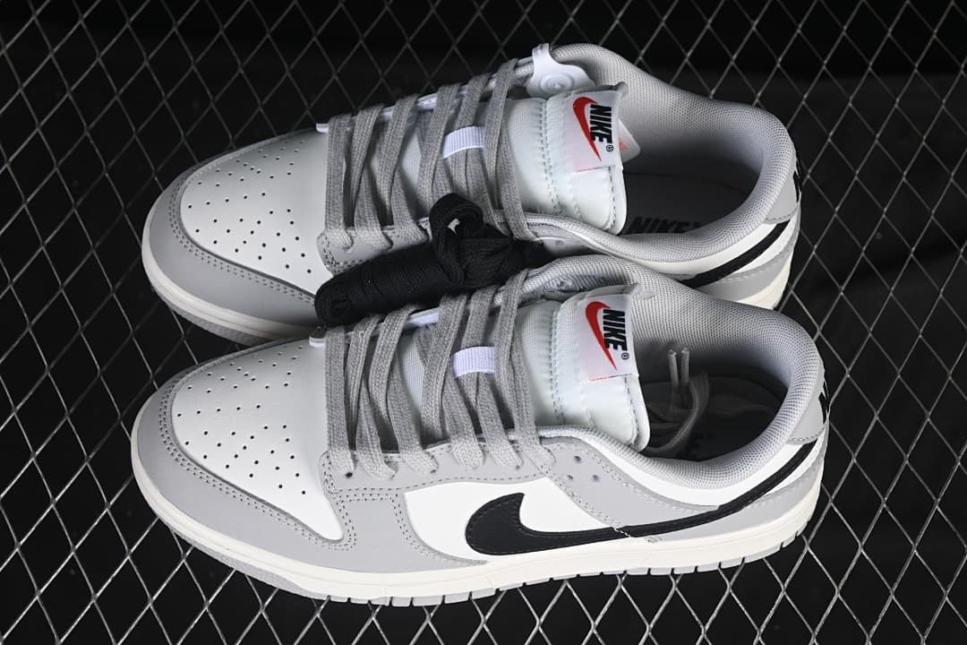 Pair of white, grey, and black low-top sneakers with alternate black laces