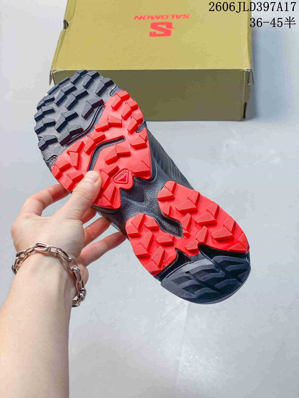 Close-up of the shoe outsole showing deep red and dark gray tread