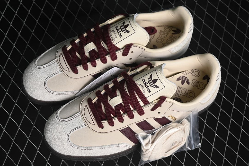 Pair of cream and burgundy Samba OG sneakers with an additional set of light-colored laces.