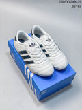White adidas Taekwondo low-top sneakers with dark stripes on a blue shoebox