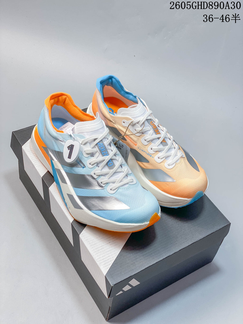 Pair of Adidas Adizero Adios Pro 4 shoes in pale blue, silver, white, and orange, shown on a box