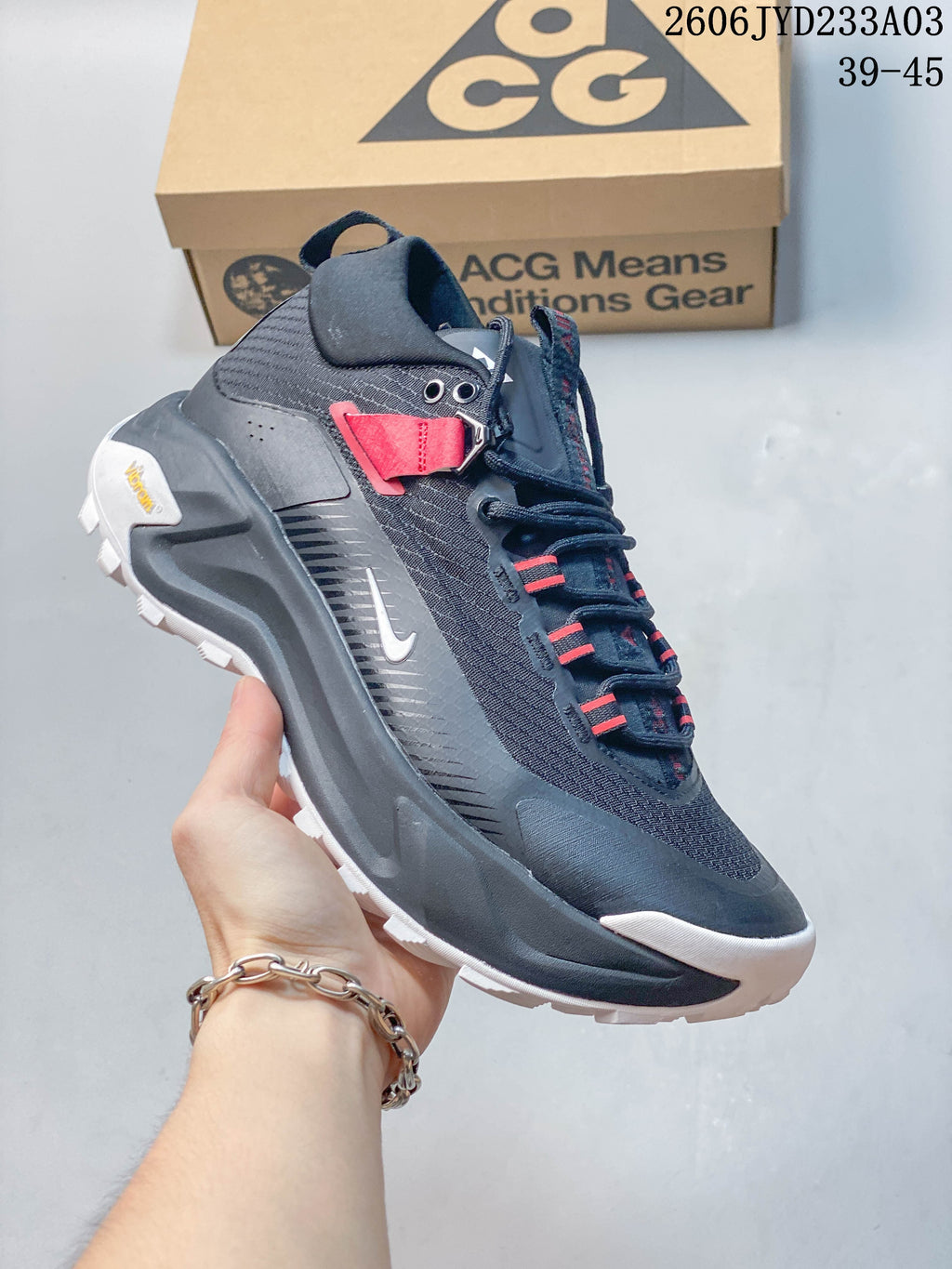 Side view of the shoe with dark upper, red accents, and white outsole