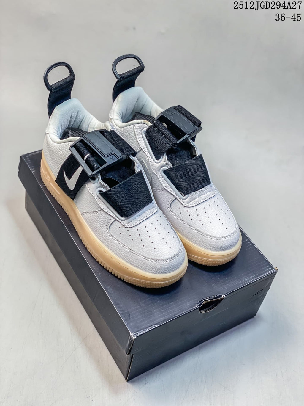 Pair of white Nike Air Force 1 Utility low-top sneakers with black straps and gum-tone soles