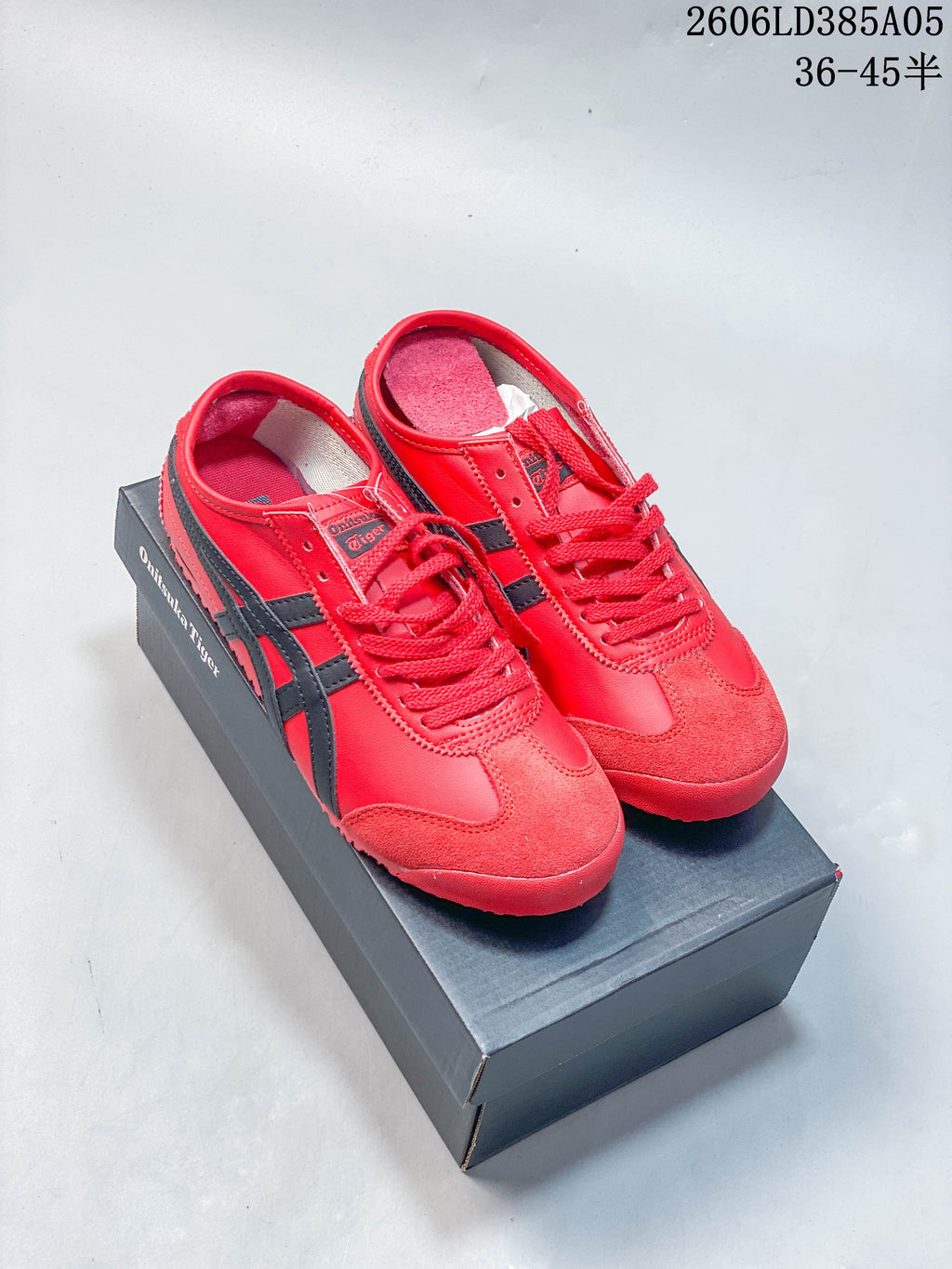 Red and dark-accented Onitsuka Tiger Mexico 66 Deluxe sneakers shown on a shoebox