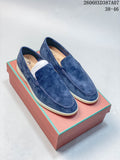 Pair of blue slip-on loafers with stitched apron toes and light-colored soles, shown on a box.