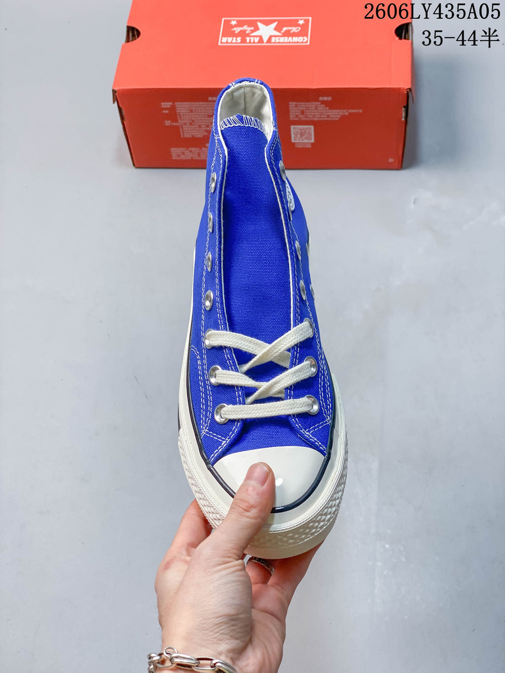 Front view of a blue high-top sneaker with white laces and a rubber toe cap