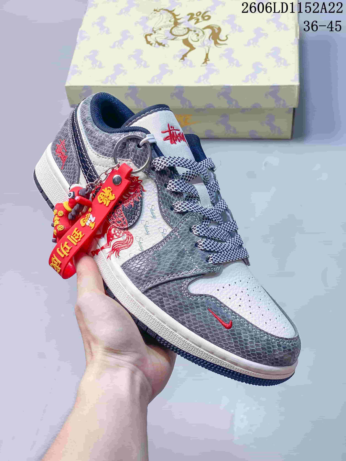 Low-top sneaker with gray patterned panels, white sections, red accents, and a decorative red charm; size range 36–45 is printed in the image.