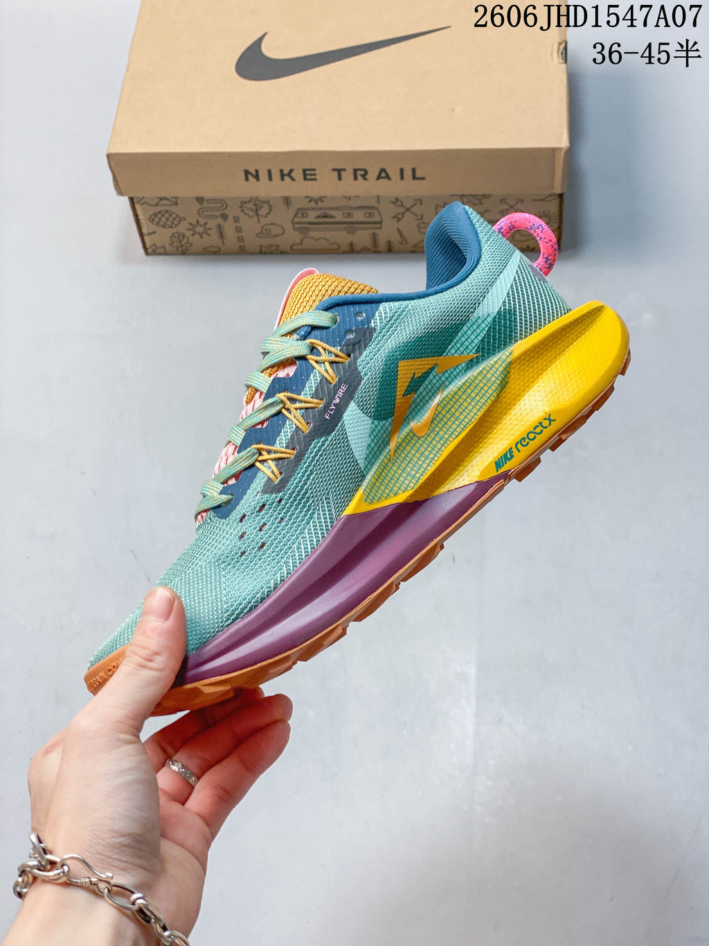 Side view of a teal Nike ReactX Pegasus Trail 5 shoe with contrasting yellow and purple midsole details.