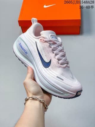 Pale pink and white Nike Vomero Plus shoe with a navy swoosh.