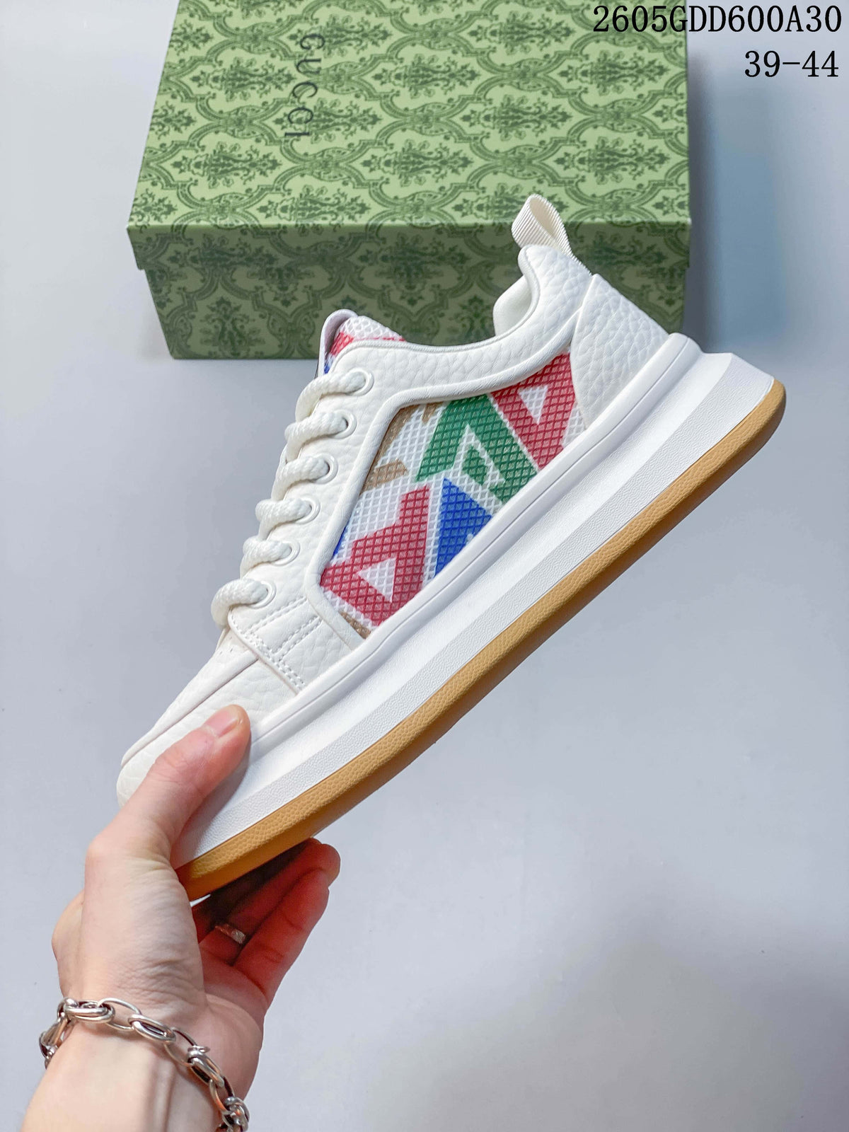 Side profile of a white sneaker with multicolor geometric panels and a gum-colored outsole.