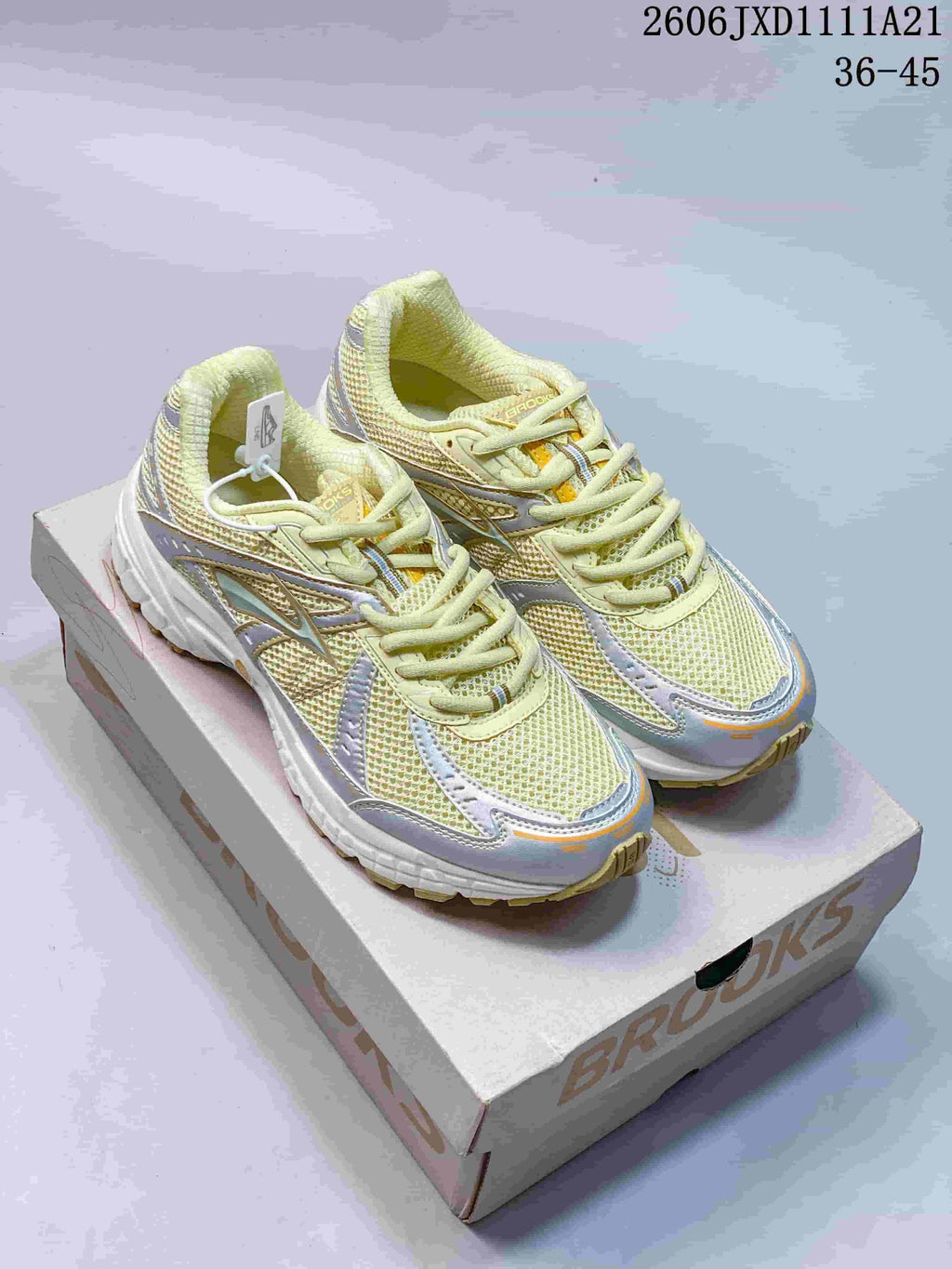 Pair of pale yellow and silver-toned Brooks Adrenaline GTS 10 sneakers on a shoe box