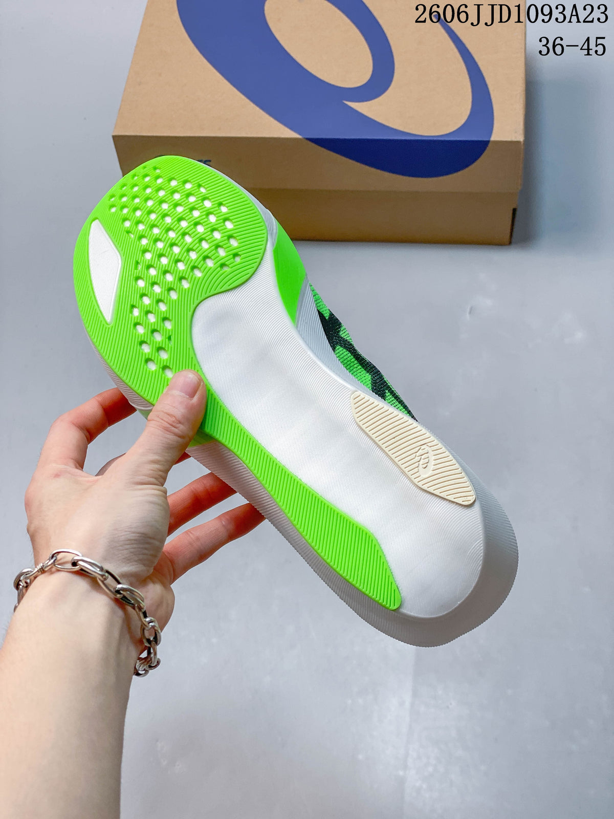 Underside of a bright green running shoe showing its white-and-green sole