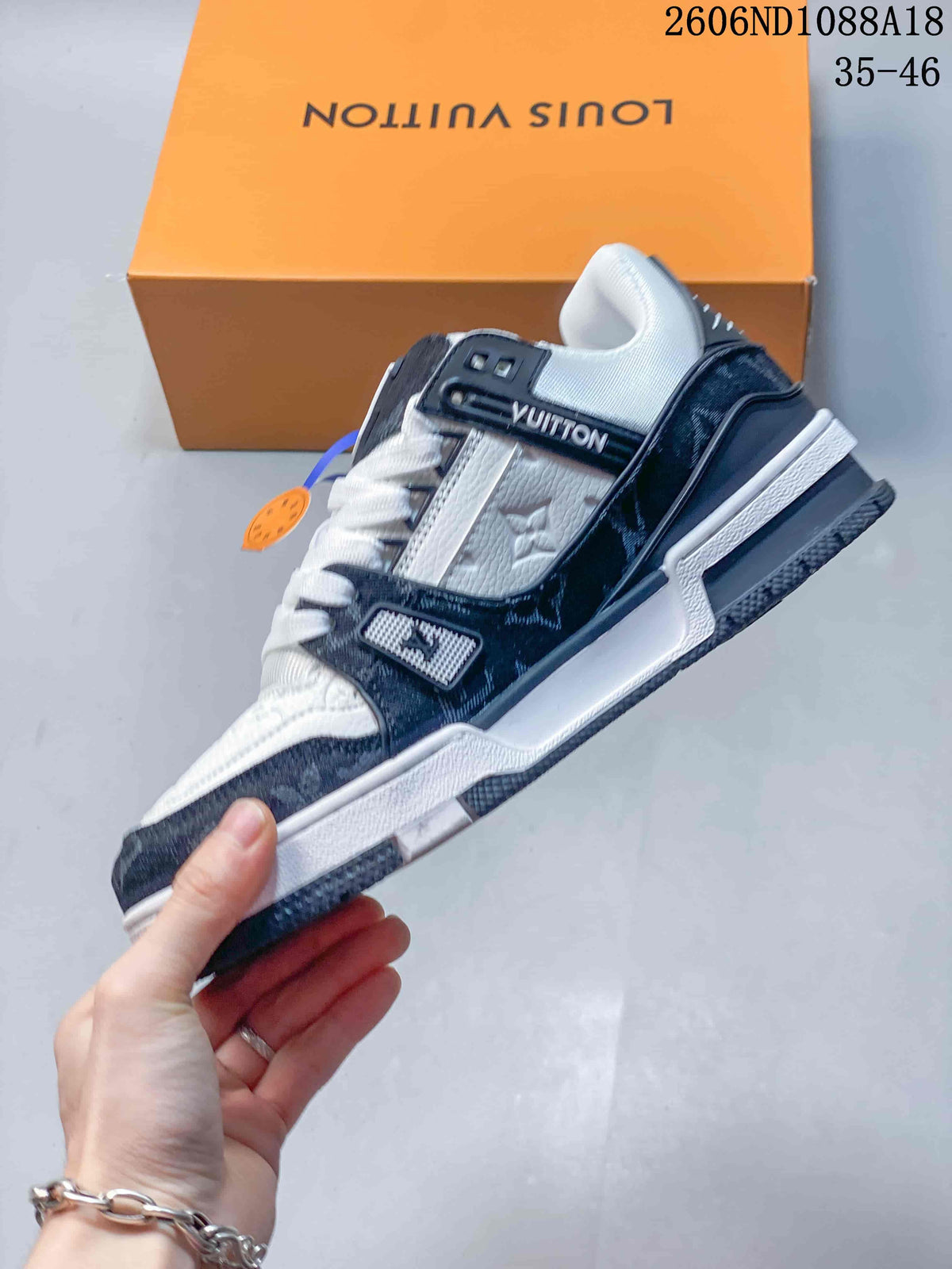 Side view of a white and navy Louis Vuitton Trainer low-top sneaker.