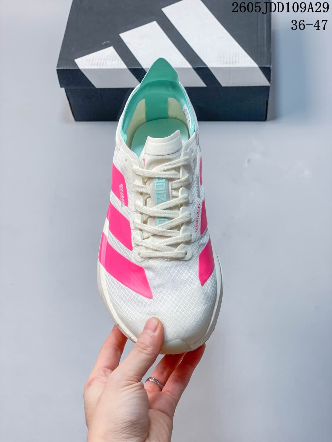 Front view of a white Adidas running sneaker with pink side panels, teal tongue branding, and a patterned upper.
