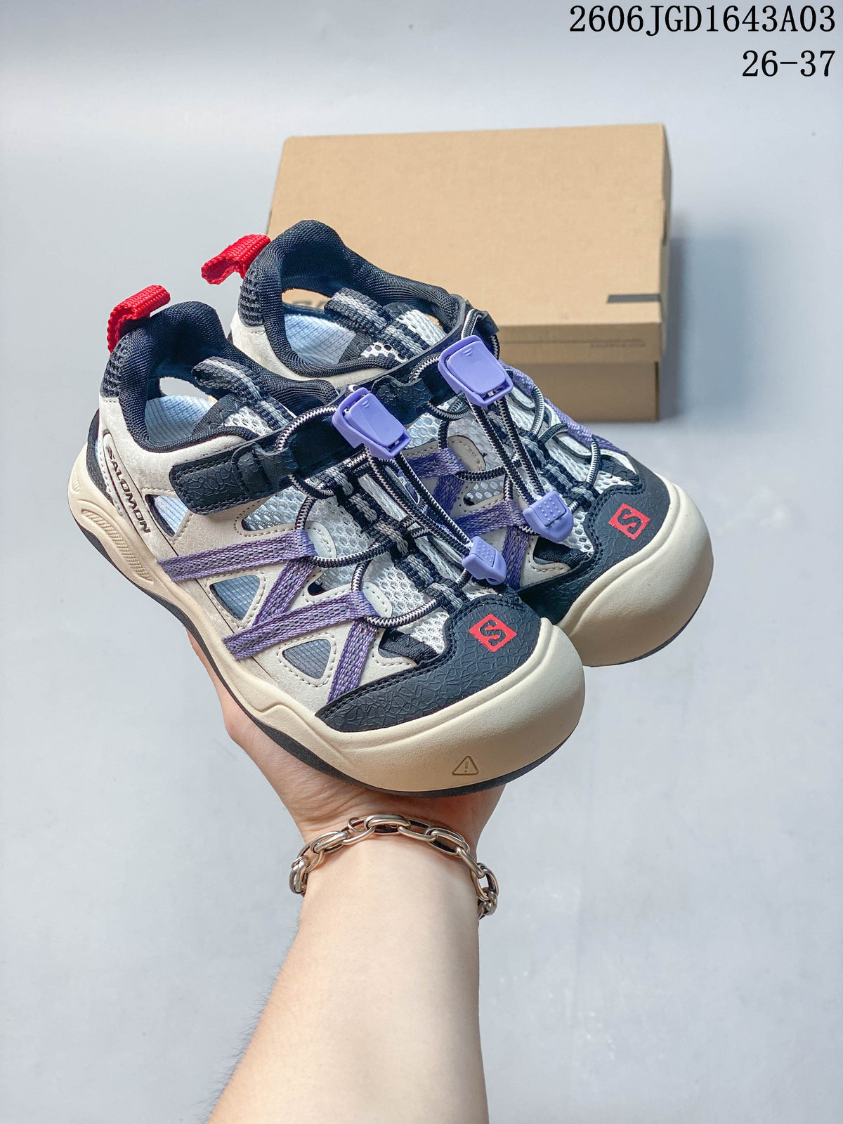 Pair of light neutral kids’ Salomon sneakers with navy, purple, and red accents.