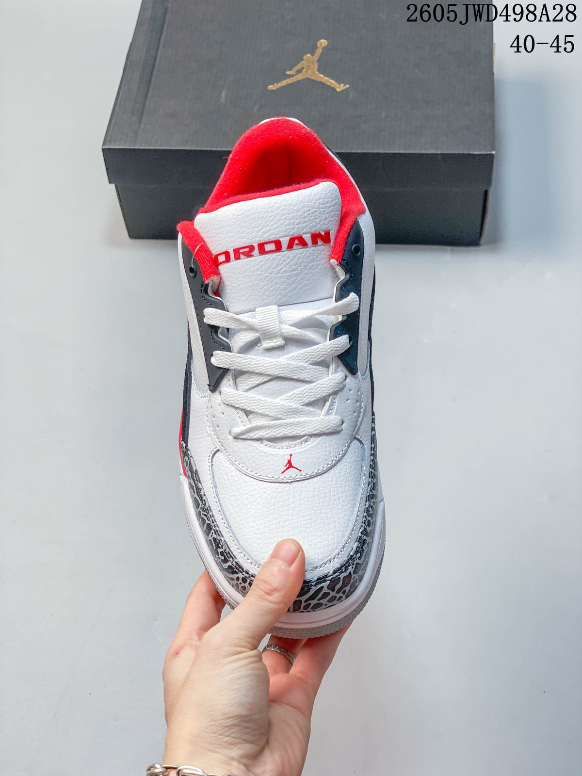 Front view of a white low-top Jordan sneaker with red tongue lining and elephant-print toe trim