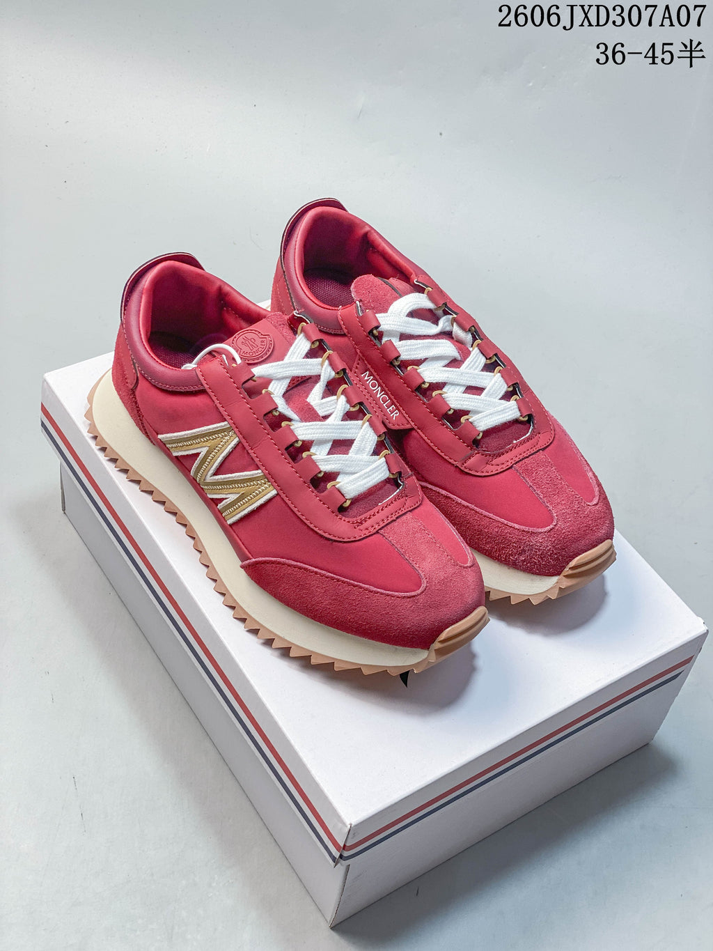 Pair of rose-pink lace-up sneakers with white laces and sawtooth outsoles on a branded presentation box.