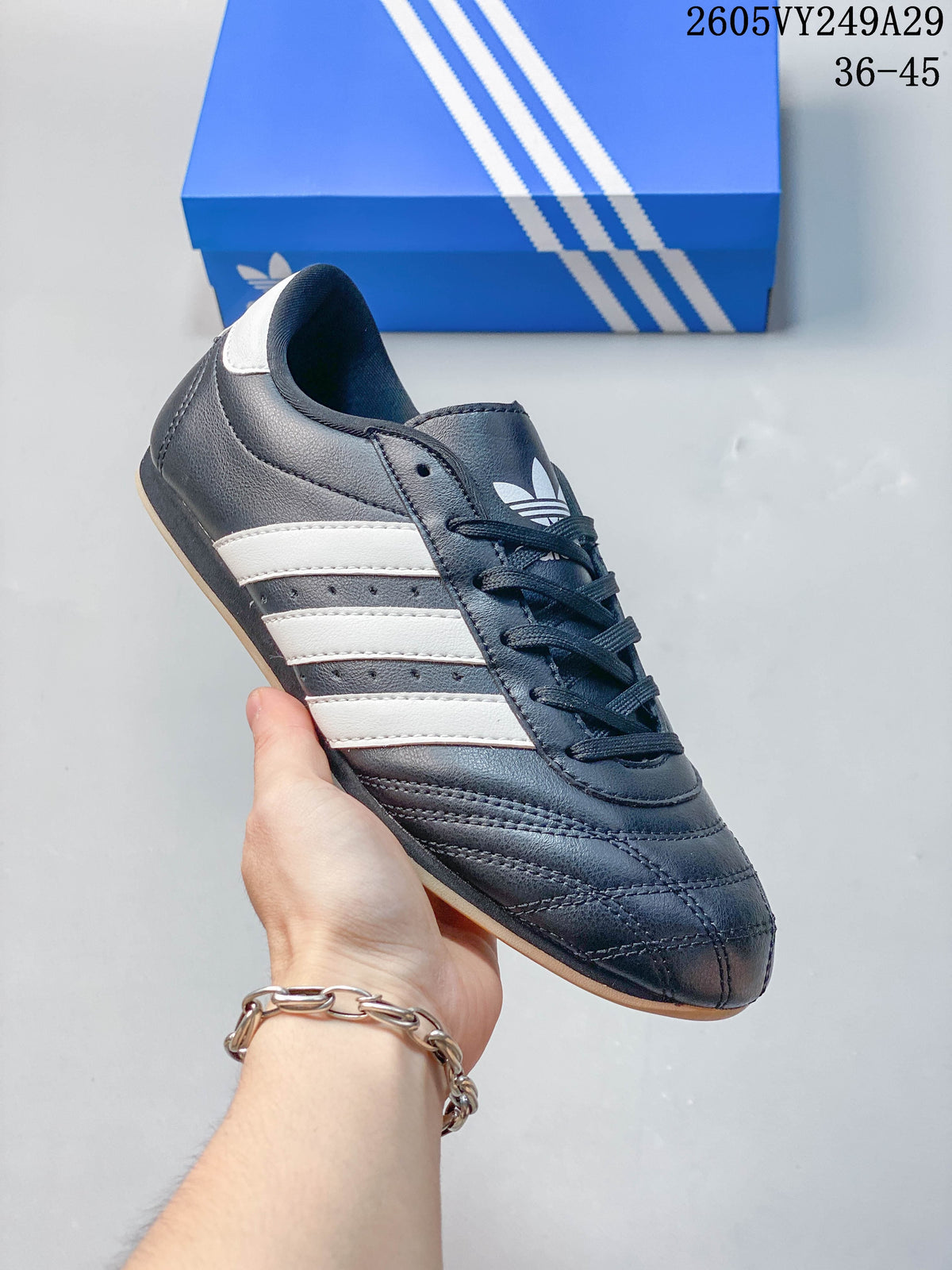 Close-up of a black low-top lace-up shoe with white stripes and stitched toe panels.